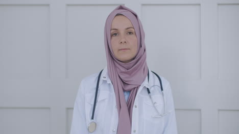 Looking-at-the-camera-listening-woman-doctor-in-hijab-looks-at-the-camera-and-listens-to-the-patient.-A-video-conference-listener.-Portrait-of-a-doctor-in-a-hijab